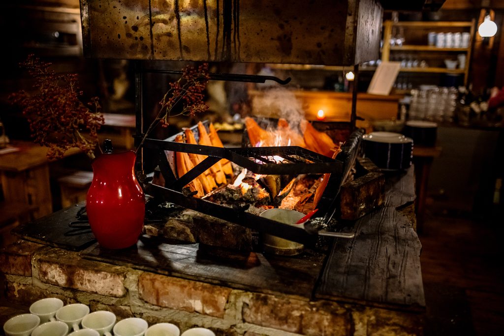 An open fireplace inside a room. There are some red fishes near the fire.